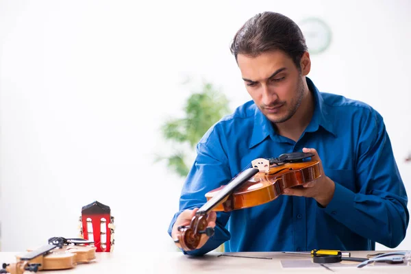 Jovem reparador do sexo masculino reparando violino — Fotografia de Stock