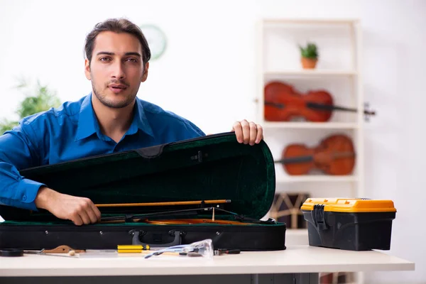 Young male repairman repairing violin