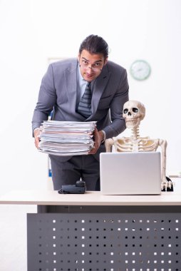 Genç erkek çalışan ve iskelet ofiste.