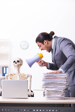 Genç erkek çalışan ve iskelet ofiste.