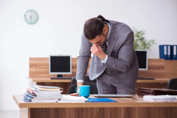 Giovane dipendente maschio infelice con il lavoro eccessivo — Foto Stock