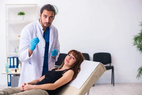 Mujer joven visitando dermatólogo médico masculino — Foto de Stock