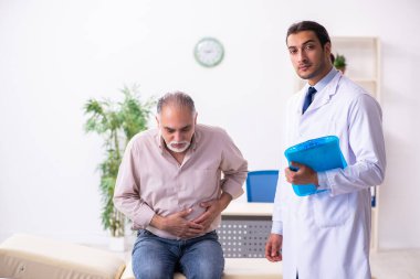 Yaşlı hasta genç erkek doktoru ziyaret ediyor.