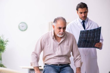 Yaşlı hasta genç erkek doktoru ziyaret ediyor.