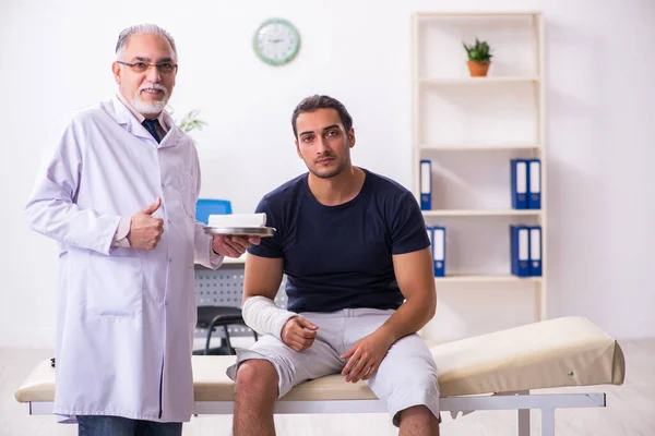 Genç yaralı adam deneyimli erkek doktor travmatologları ziyaret ediyor. — Stok fotoğraf