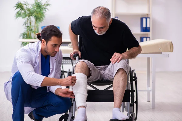 Viejo hombre herido visitando joven médico traumatólogo —  Fotos de Stock