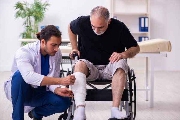 Old injured man visiting young male doctor traumatologist