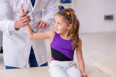 Küçük kız genç erkek doktoru ziyaret ediyor.