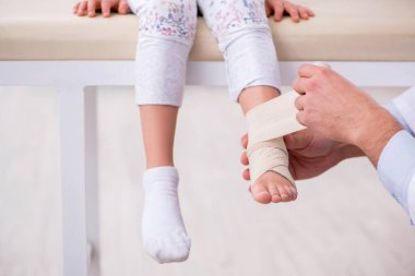 Küçük kız genç erkek doktoru ziyaret ediyor.