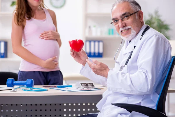 Jovem mulher grávida visitando velho médico ginecologista masculino — Fotografia de Stock