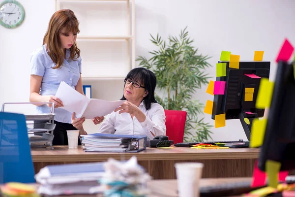Две женщины-сотрудницы и чрезмерная работа в офисе — стоковое фото