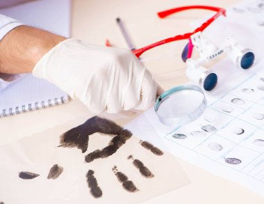 Forensic expert studying fingerprints in the lab clipart