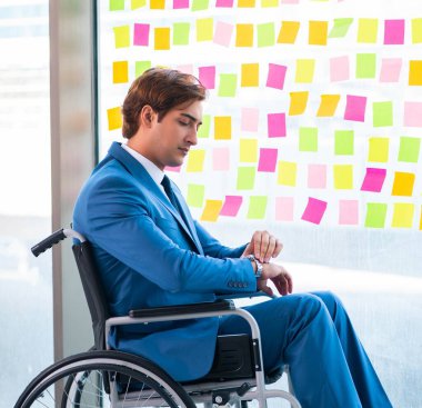 Birçok çelişkili önceliği olan tekerlekli sandalyedeki genç yakışıklı adam.