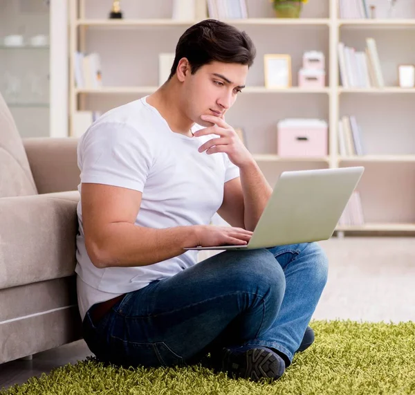 Homem trabalhando no laptop em casa no chão do tapete — Fotografia de Stock