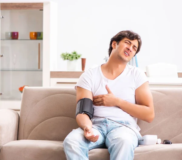 Hombre joven midiendo la presión arterial en casa — Foto de Stock