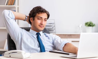Genç yakışıklı işadamı ofiste çalışıyor.