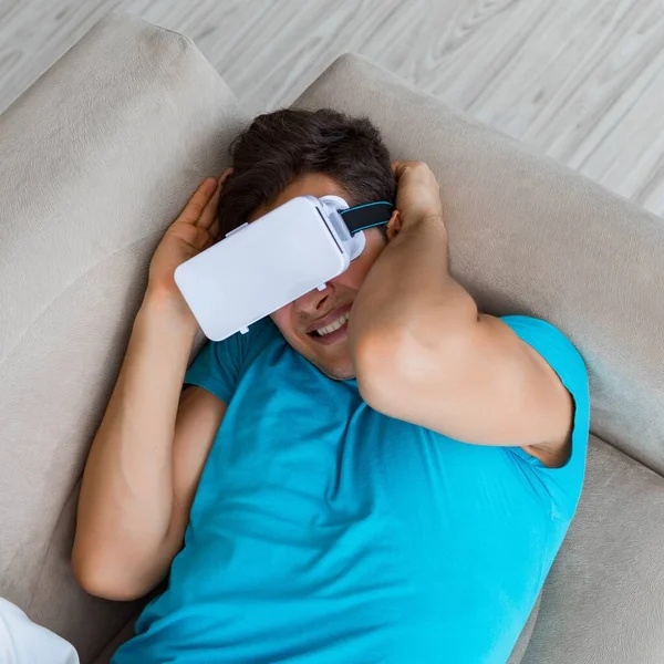 Молодий чоловік в окулярах VR, що розслабляються на дивані — стокове фото