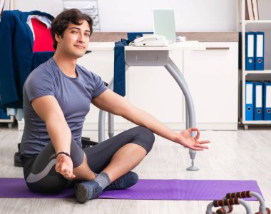 Ofiste egzersiz yapan genç bir erkek.