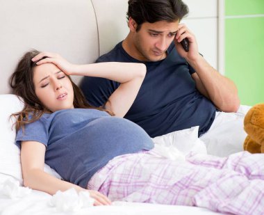 Genç koca hamile karısına bakıyor.