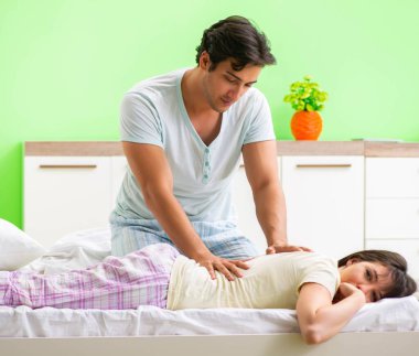 Adam yatak odasında karısına masaj yapıyor.