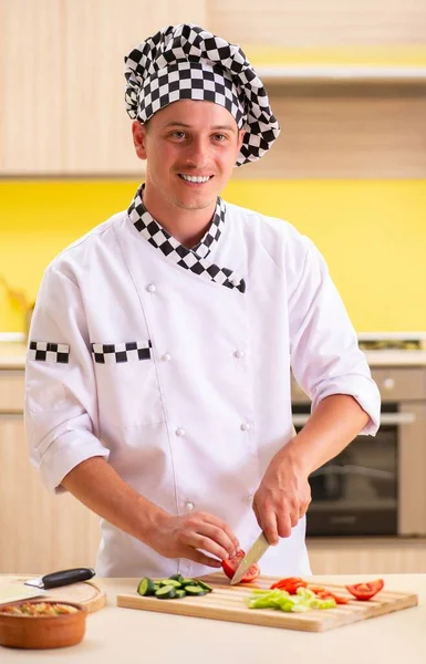 Jovem cozinheiro profissional preparando salada na cozinha — Fotografia de Stock