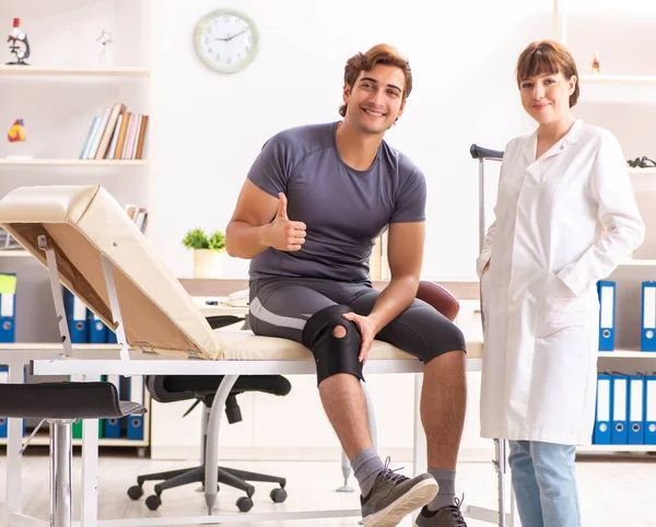 Handsome american footbal player visiting female doctor traumato — Stock Photo, Image