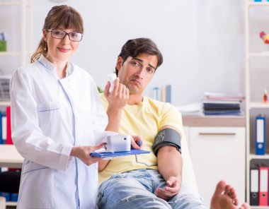 Genç doktor hastaların tansiyonunu ölçüyor.