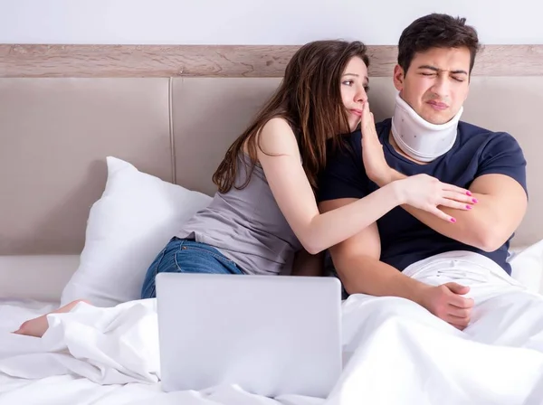 Liebevolle Ehefrau kümmert sich um verletzten Ehemann im Bett — Stockfoto