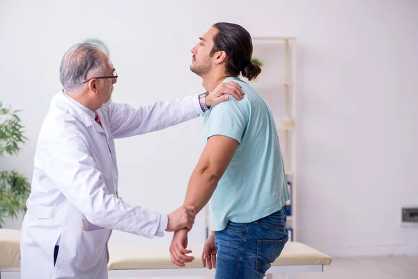 Young back injured man visiting experienced male doctor — Stock Image Young back injured man visiting experienced male doctor Royalty Free Stock Photos