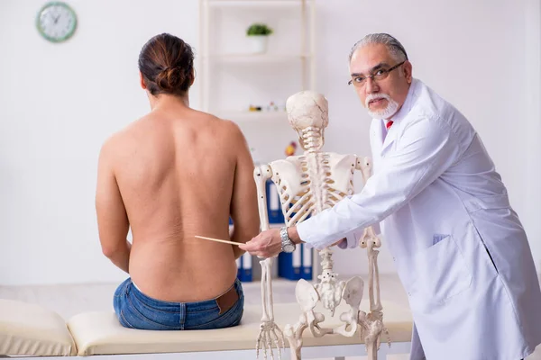 Young back injured man visiting experienced male doctor — Stock Image Young back injured man visiting experienced male doctor Stock Photo
