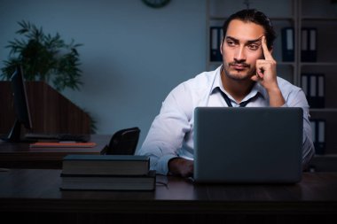 Gece ofiste çalışan genç bir erkek.
