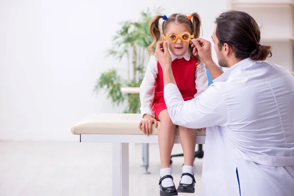 Menina pequena visitando jovem médico oculista masculino — Fotografia de Stock