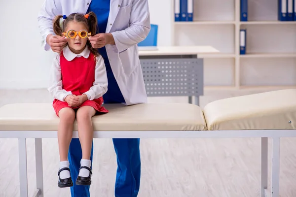 Menina pequena visitando jovem médico oculista masculino — Fotografia de Stock
