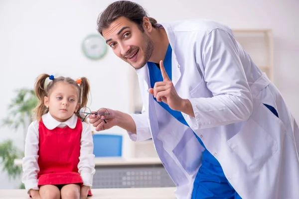 Маленькая девочка, навещающая молодого врача-окулиста — стоковое фото