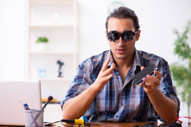 Cep telefonunu tamir eden genç bir teknisyen.