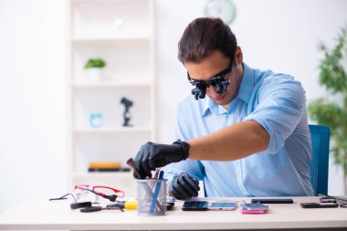 Cep telefonunu tamir eden genç bir teknisyen.