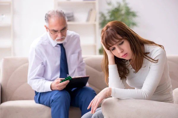 Mujer joven visitando viejo médico psicólogo — Foto de Stock