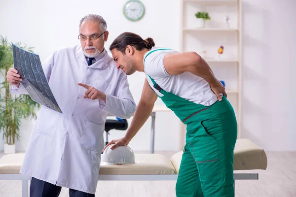 Young male contractor visiting old doctor — Stock Photo, Image