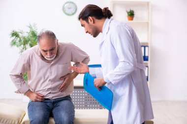 Yaşlı hasta genç erkek doktoru ziyaret ediyor.