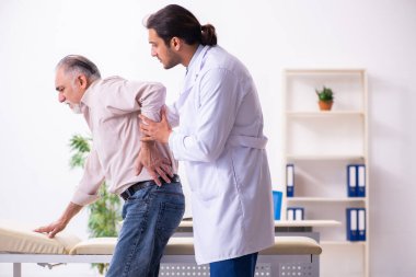 Yaşlı hasta genç erkek doktoru ziyaret ediyor.