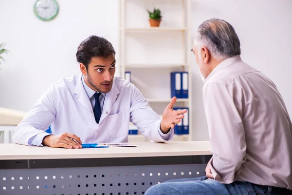 Oude patiënt op bezoek bij jonge mannelijke arts — Stockfoto