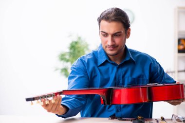 Gitarı tamir eden genç bir erkek tamirci.