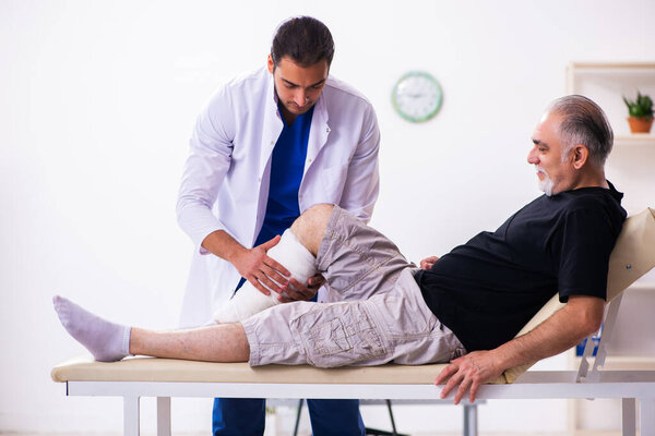 Old injured man visiting young male doctor traumatologist