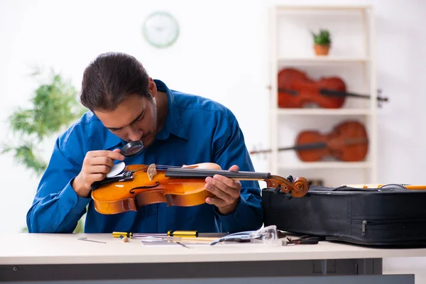 Jovem reparador do sexo masculino reparando violino — Fotografia de Stock