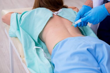 Genç sırtı yaralı kadın, erkek doktor masörünü ziyaret ediyor.