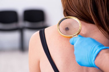 Genç bir kadın erkek doktor dermatoloğunu ziyaret ediyor.