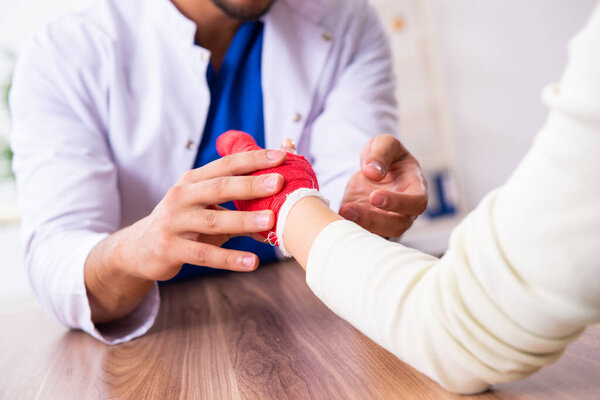 Young hand injured woman visiting male doctor traumatologist