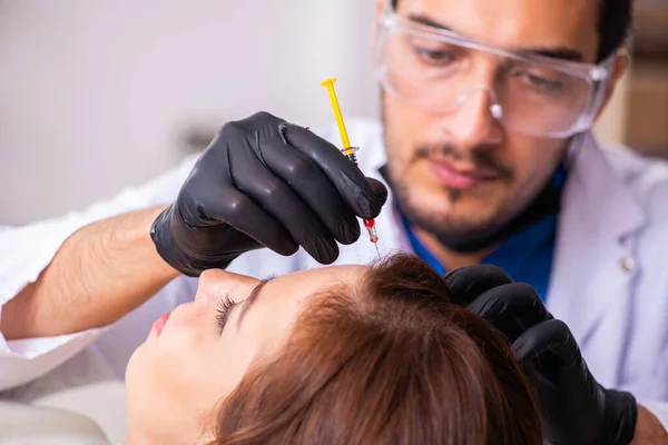 Ung kvinna besöker manlig kosmetolog i hår transplantation con — Stockfoto