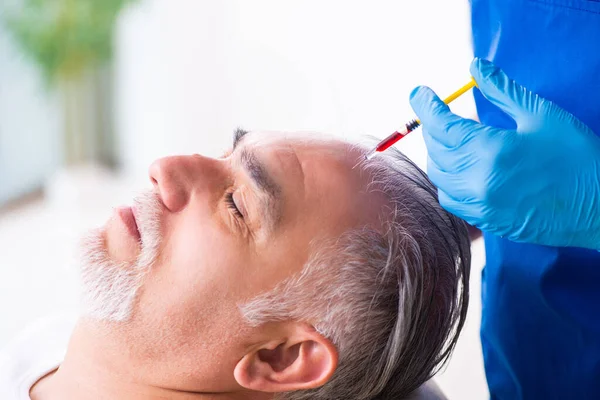 Old man visiting young male doctor in hair transplantation conce — Stock Photo, Image