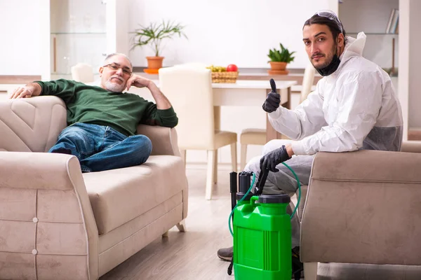 Young male sanitizer and old man indoors